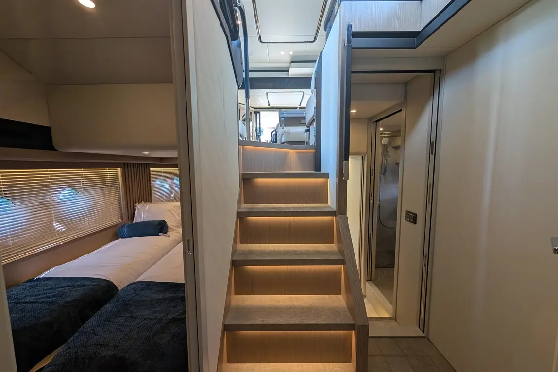 Interior view of modern stairway with illuminated steps, leading to a stylish living space next to a bedroom.